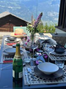 韦尔科兰Chalet Familial Capricorne的一张带盘子和玻璃杯的桌子和一瓶葡萄酒