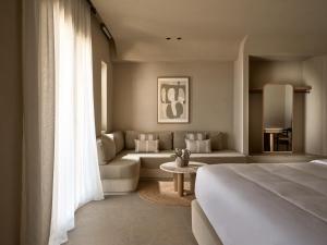 米克诺斯城Domes Noruz Mykonos的一间卧室设有一张床和一间客厅。