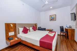 孟买J Hotel and Banquets的卧室配有一张床、一张桌子和椅子