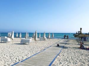 坎帕斯蒂利亚Apartamento delante del mar的海滩上设有白色的遮阳伞和椅子,还有大海