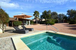 科斯提克斯Casa con piscina en bonito entorno Mia的一个带两把椅子和遮阳伞的游泳池