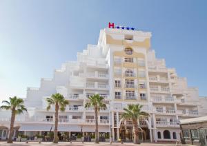 拉曼加戴尔马尔梅纳海豚酒店的一座白色的大建筑,前面有棕榈树