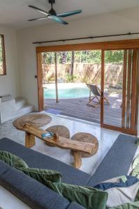 吉利阿尔Villa Luna - Gili Air的一间带桌椅的客厅和一个游泳池
