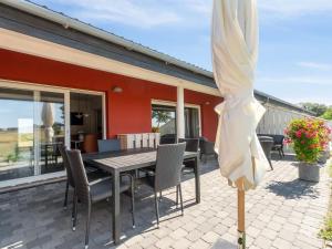 奥基克比Apartment Cornelia - 6km from the sea in Bornholm by Interhome的庭院配有桌椅和遮阳伞。