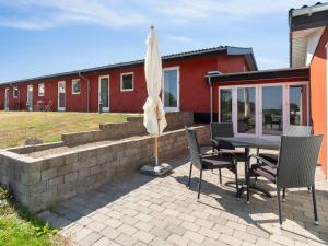 奥基克比Apartment Cornelia - 6km from the sea in Bornholm by Interhome的庭院配有桌椅和遮阳伞。