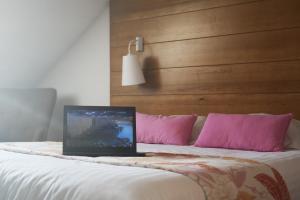 Grande Riviere卢格兰瓦酒店的笔记本电脑坐在床上,床上有粉红色枕头