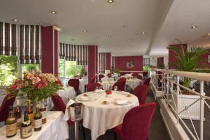 SolesmesGrand Hôtel de Solesmes - Teritoria的餐厅设有白色桌子和红色椅子,并提供葡萄酒瓶
