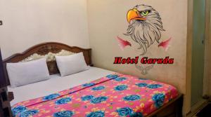 RambahHotel Garuda的卧室配有一张床上,墙上涂有鸟