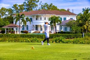 Ban Nong SaiThe White House, Palm Hills Golf and Country Club的一个人在房子前打高尔夫球