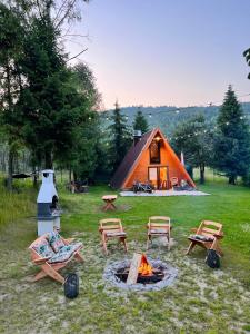拉伊恰Domek nad Potokiem w Beskidach的一个带椅子的帐篷和一个草地上的火坑