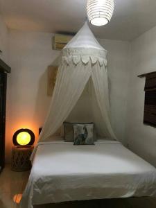 圣吉吉Frangipani Garden Villa的卧室内的白色床和天蓬