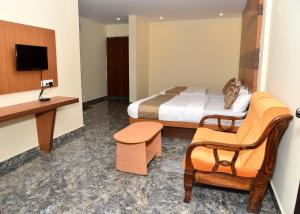 维拉杰佩特Sanjose Residency的配有一张床和一把椅子的酒店客房