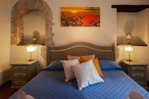 巴尼奥维尼奥尼Locanda Il Porcellum的一间卧室配有蓝色的床、枕头和绘画