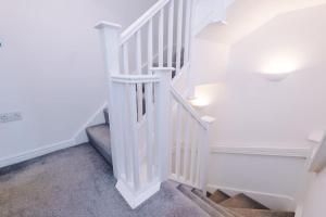 RothwellLuxury 3-bed house - Rothwell Gardens - 10mins from Leeds city centre的白色的楼梯,有白色的墙壁和地毯