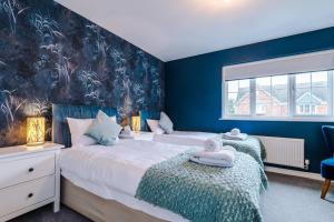 RothwellLuxury 3-bed house - Rothwell Gardens - 10mins from Leeds city centre的卧室设有两张床铺和蓝色的墙壁