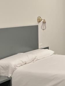 毕尔巴鄂Apartamentos Lidar的一张带白色床单的床和墙上的一盏灯