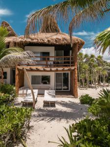 图卢姆Niken Beachfront Tulum Hotel的海滩上带茅草屋顶的房子