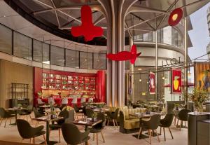 伦敦art'otel London Battersea Power Station, Powered by Radisson Hotels的一间带桌椅的餐厅和一间酒吧