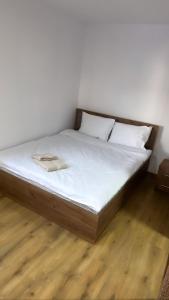 阿尔杰什河畔库尔泰亚Popas Momaia的铺有木地板的一张带白色床单和枕头的床