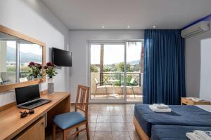 玛利亚Aeolos Beach Resort的酒店客房配有一张床、一张书桌和一台笔记本电脑