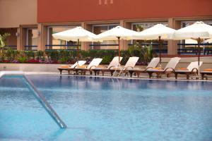 亚历山大亚历山大绿色广场希尔顿酒店的酒店游泳池设有椅子和遮阳伞