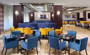 亚历山大亚历山大绿色广场希尔顿酒店的餐厅设有蓝色和黄色的椅子和桌子