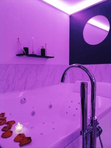 梅斯L'Atelier de rêves的浴室设有白色浴缸和紫色照明