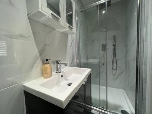 亨顿Star London Bell Lane 3-Bed Oasis with Garden的白色的浴室设有水槽和淋浴。