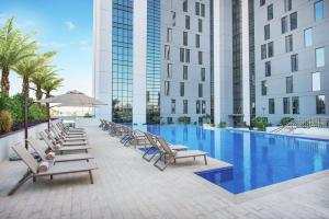 迪拜迪拜机场汉普顿酒店 的一个带躺椅的游泳池和一间酒店