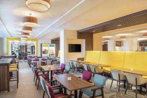 迪拜迪拜机场汉普顿酒店 的餐厅设有桌椅和黄色的墙壁