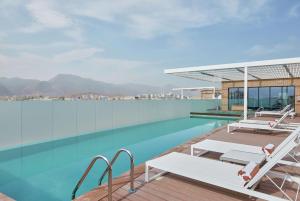 马斯喀特Hilton Garden Inn Muscat Al Khuwair的一座带两把躺椅的游泳池位于一座建筑的顶部