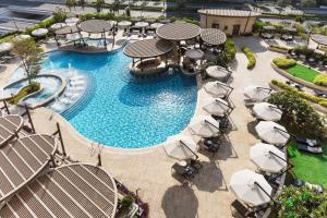 多哈Hilton Doha The Pearl的享有带椅子和遮阳伞的游泳池的上方景致
