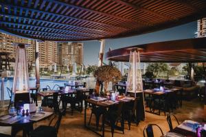 多哈Hilton Doha The Pearl的一间带桌椅的餐厅和一个游泳池