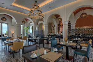 HauaraHilton Tangier Al Houara Resort & Spa的一间带桌椅和吊灯的餐厅