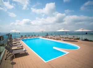 伊斯坦布尔伊斯坦布尔莫达希尔顿逸林酒店 的一座大楼内的游泳池,配有椅子和遮阳伞