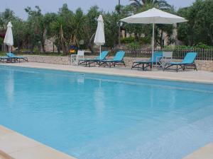 圣凯撒利亚温泉Residence Conchiglia San Giovanni的一个带蓝色椅子和遮阳伞的游泳池