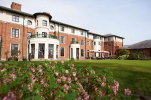 格洛斯特Hilton Puckrup Hall Hotel & Golf Club, Tewkesbury的前面有粉红色花的砖砌大建筑