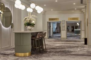 格拉斯哥希尔顿格拉斯哥酒店的大堂设有酒吧,提供椅子和花瓶
