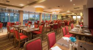 卢顿希尔顿北卢顿花园酒店的餐厅设有木桌和红色椅子