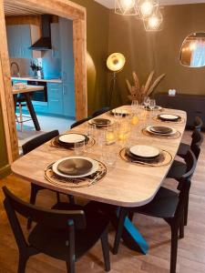 热拉梅Maison Les Planches的一张木桌,上面放有盘子和酒杯