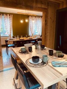 热拉梅Maison Les Planches的用餐室配有木桌和玻璃杯椅子