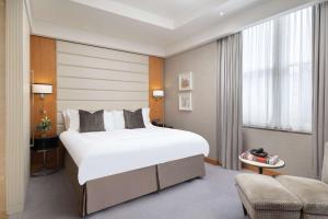 伦敦伦敦圣詹姆斯康拉德酒店的卧室配有一张白色大床和一把椅子