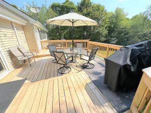 Long PondWOW!! Ultimate Pocono Retreat, Hot Tub, Game Room, Deck, Lakes, Skiing, Pools的木甲板配有桌子和遮阳伞