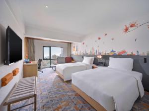 广州Hilton Garden Inn Guangzhou Tianhe- Free Canton Fair Shuttle Bus的酒店客房设有两张床和电视。