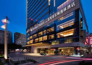 重庆重庆嘉发希尔顿逸林酒店的一座大型建筑,前面有停车位