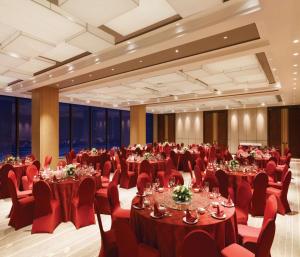 丹东丹东希尔顿花园酒店的宴会厅配有桌子和红色椅子
