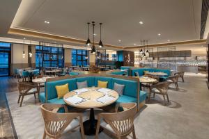 九寨沟九寨鲁能希尔顿花园酒店的餐厅设有蓝色的沙发和桌椅