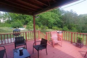 Cozy Old House in Lost Creek PA: Enchanting Deck and Expansive Yard.的木制甲板配有椅子、桌子和灯