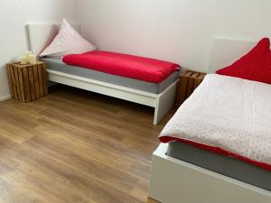 瓦尔茨胡特田根Ferienwohnung am Liederbach的一间卧室配有两张带红色枕头的床,铺有木地板