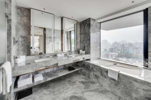 台北台北中山九昱希尔顿逸林酒店的一间带两个盥洗盆、浴缸和窗户的浴室